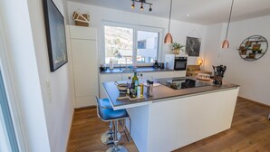 Una cocina moderna con una isla grande, armarios blancos y vistas al exterior a través de un amplio ventanal.