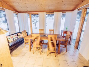 Cozy dining area with a wooden table and six chairs, offering a view of the surrounding landscape.