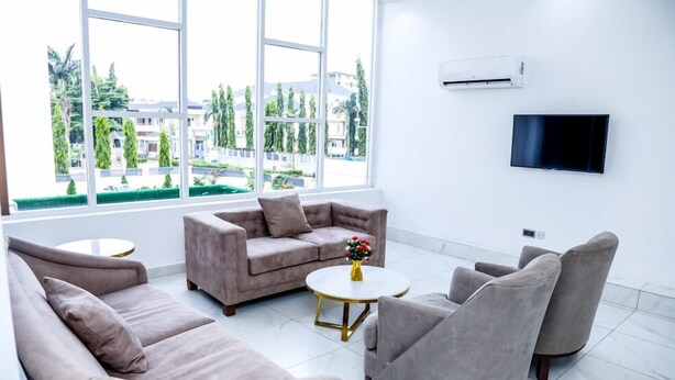 A modern living room with a sofa set, a coffee table, and a flat-screen TV mounted on the wall. - Stratton 38 Asokoro (Abuja)