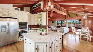 A spacious kitchen with a large island, stainless steel appliances, and a wooden ceiling.