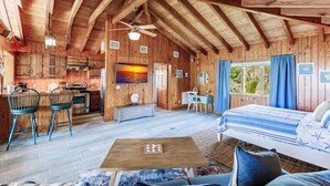 A rustic cabin interior with a kitchen, dining area, and a bedroom.