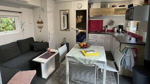 Ein kompakter Wohnbereich mit Küchenzeile, Essbereich und einer Sitzecke mit Sofa und kleinem Tisch.