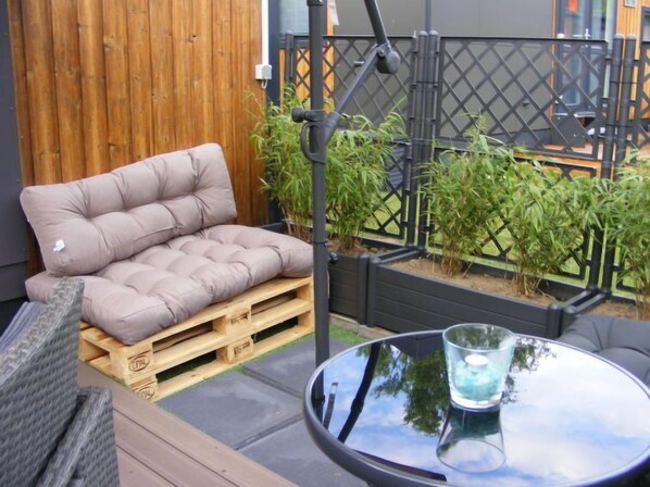 A patio with a cushioned seating area, a round table with a glass top, and a metal fence. - Tiny Haus Ulrike by Interhome (Wemding)