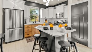 A modern kitchen with stainless steel appliances, a central island with stools, and a clock on the wall. - Red Mountain Villa, Game Room, Community Pool, Smart Tv's (Washington)
