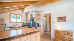 Une cuisine moderne avec des meubles en bois, un grand îlot central et une vue sur l’espace de vie.