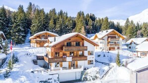 Une station de ski enneigée, avec des bâtiments en bois, des balcons et un paysage montagneux en toile de fond.