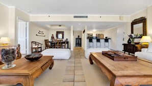 Une chambre d’hôtel comprenant un coin repas, une cuisine et un salon avec des meubles en bois et un grand miroir.