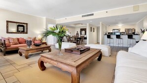 Un vaste espace de vie comprenant un canapé, une table basse et, au fond, un coin repas.