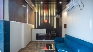 A reception area with a modern design, featuring a reception desk, a blue sofa, and a patterned wall. - Kiran Palace Varanasi (Varanasi)