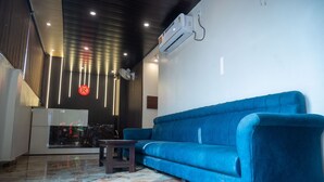 A modern interior with a blue sofa, a small table, and a large mirror. - Kiran Palace Varanasi (Varanasi)