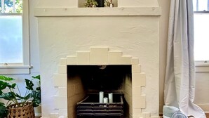A fireplace with a brick surround, a small shelf above it, and a window to the left.