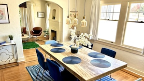 A dining area with a wooden table, blue chairs, and a vase with white flowers.
