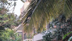 Um edifício de vários andares com varandas, rodeado por vegetação densa e árvores.