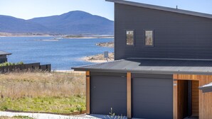 Et moderne hus med garage og udsigt til en sø og bjerge.