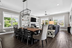 A modern kitchen with a dining area, built-in shelves, and a large window.