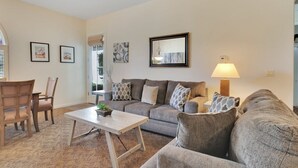 Een woonkamer met een bank, stoelen, een salontafel en een lamp.
