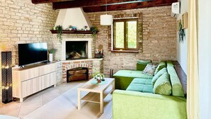 A cozy living room with a fireplace, a television, and a green sofa. - Beautiful home in Cabrunici (Cabrunici)