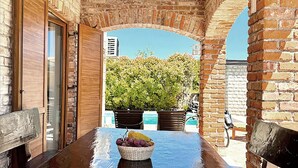 A patio area with a table, chairs, and a basket of fruit. There is a brick wall and a view of trees and buildings in the background. - Beautiful home in Cabrunici (Cabrunici)
