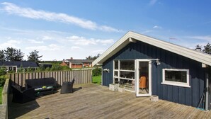 A wooden deck with a barbecue area, a covered seating area, and a small shed with a window.