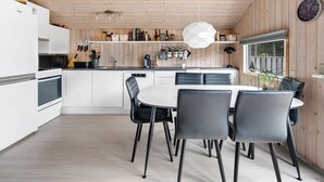 A modern kitchen with white cabinets, a central island, and a dining area with a white table and black chairs.