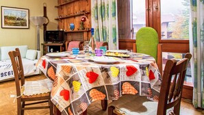 Un comedor con una mesa redonda cubierta por un mantel estampado, rodeado de sillas de madera.