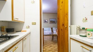 Una cocina compacta con armarios blancos, una puerta de madera y piso a cuadros.