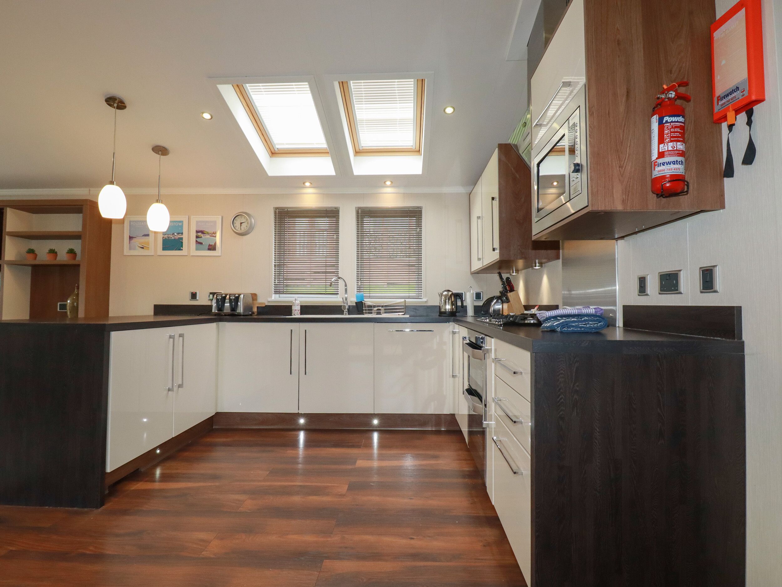 A modern kitchen with skylights, a built-in oven, and a fire extinguisher.