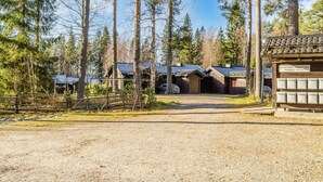 A gravel driveway leading to a row of cabins with a wooden fence and trees in the background.