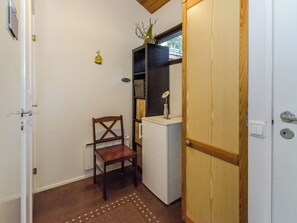 Un cuarto pequeño y cerrado con una silla de madera, un armario blanco y una puerta de madera.