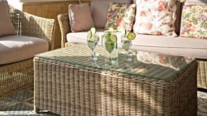 A wicker sofa with floral cushions, a glass-top coffee table with three glasses of a lime-based beverage, and a wicker chair. - Casa Germaine by Interhome (Jávea)