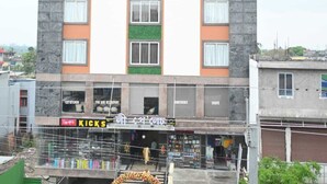 A multi-story building with a ground-level retail space labeled "KICKS" and "LEE KITCHEN."