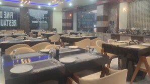 Un restaurante con varias mesas y sillas, algunas con vasos de agua y cubiertos.