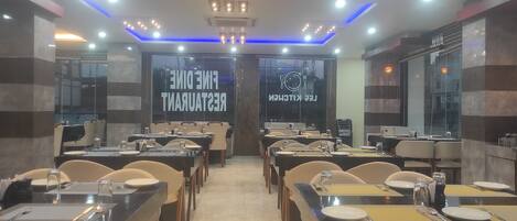 A restaurant interior with multiple dining tables and chairs, a modern ceiling design with blue lighting, and a sign reading "Fine Dining Restaurant".