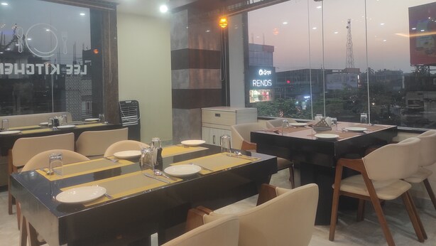 Un restaurante con mesas dispuestas para comer, vista panorámica de la ciudad a través de amplios ventanales y diseño interior moderno.