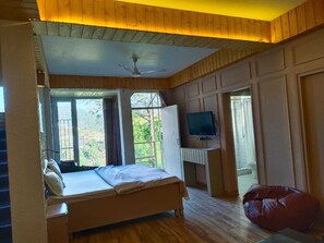 A bedroom with a bed, a TV, a window, and a wooden ceiling. - Sunrise Cottages Kasauli (Kasauli)