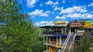Une structure à plusieurs niveaux, agrémentée de panneaux indiquant l’emplacement de l’hôtel et du café Sunrise Cottage, et offrant des commodités telles que des terrasses accessibles gratuitement et un parcours ludique avec un petit train.