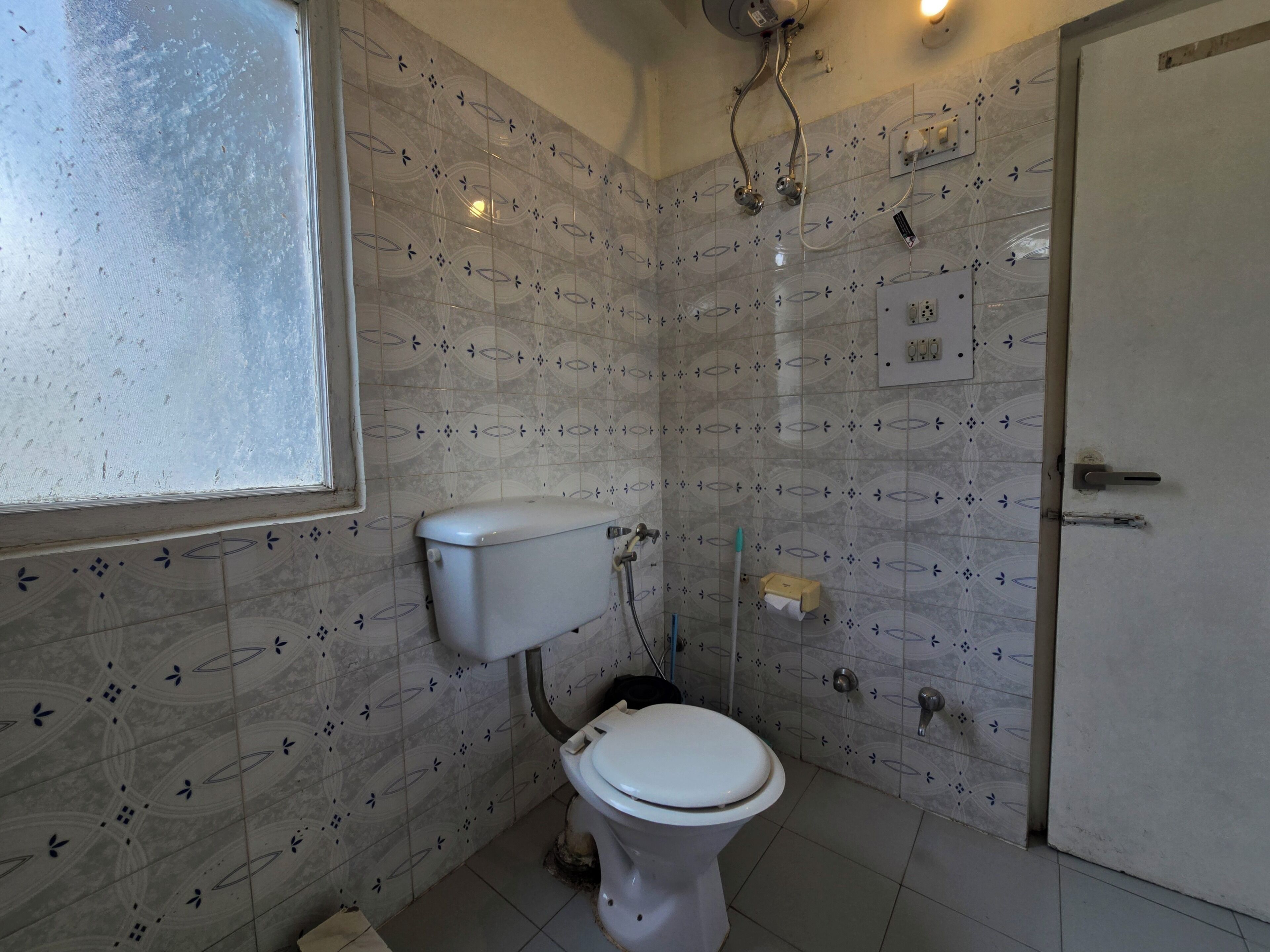 A bathroom with a toilet, a shower, and a window.