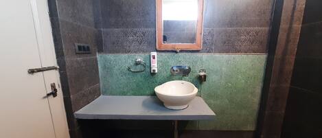 A bathroom with a white sink, a mirror, and a shower area.