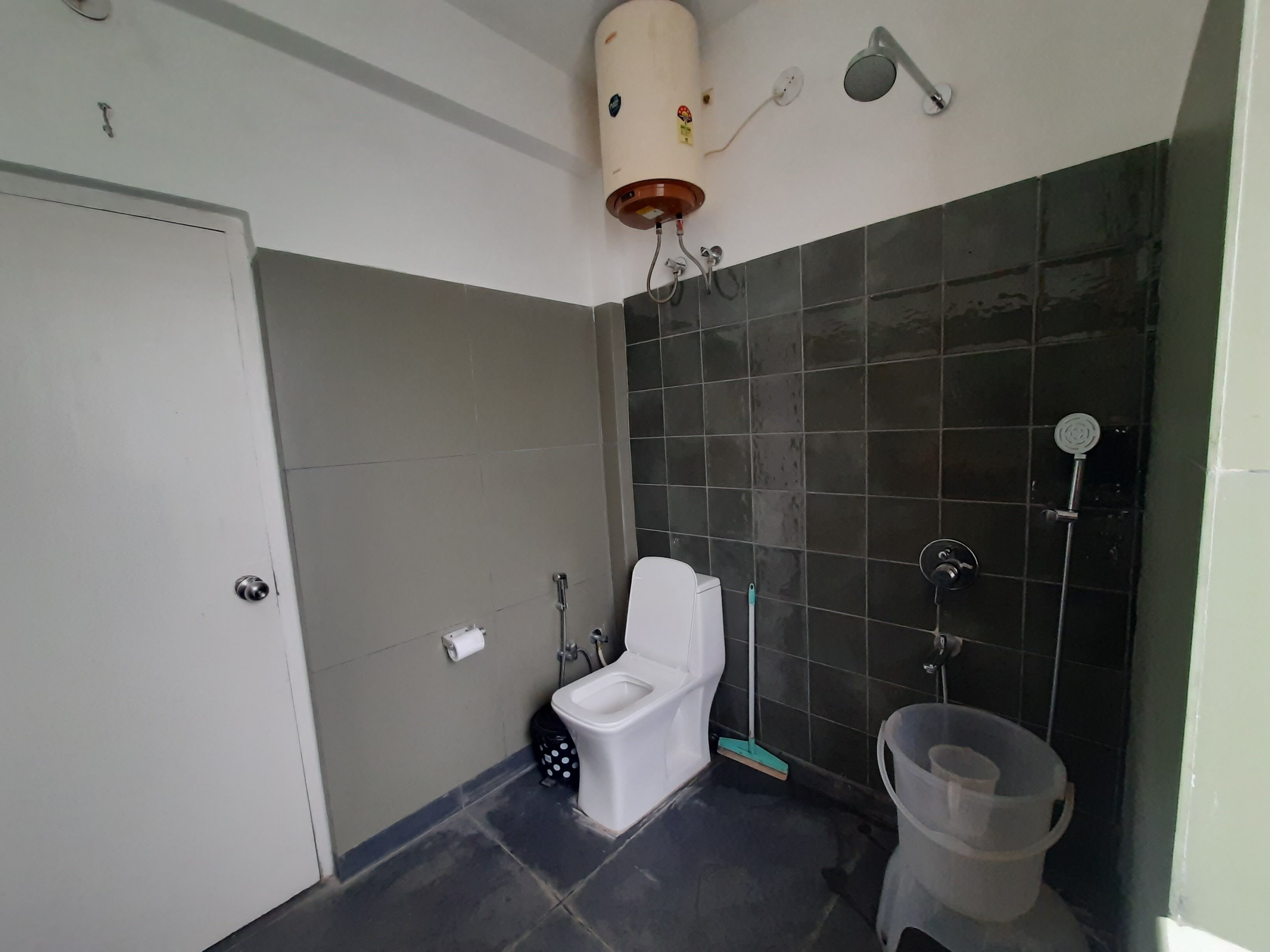 A bathroom with a toilet, a shower, and a hand dryer.
