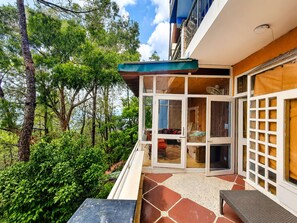 Un immeuble résidentiel doté d’un patio couvert, d’une entrée avec porte-fenêtre coulissante et offrant une vue sur une forêt verdoyante et luxuriante.