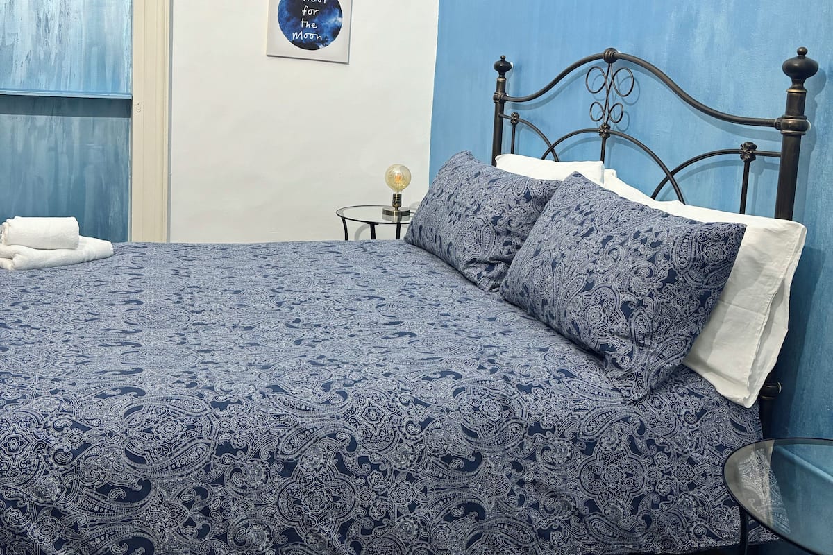 Quarto com cama, mesa de cabeceira e parede com três quadros.