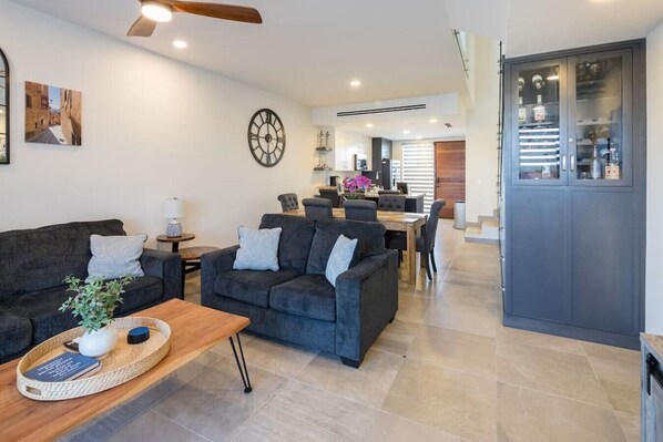 Un salon moderne avec un canapé, une table basse et un coin repas à l’arrière-plan.
