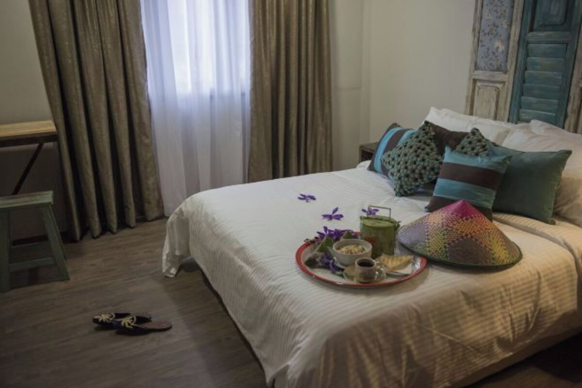 A neatly made bed with a tray of breakfast items, including a drink, a bowl, and a plate with food.