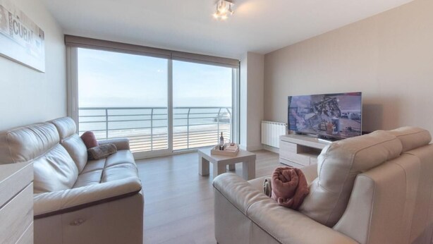 A modern living room with a sofa, a coffee table, and a television. - Modern apartment with beautiful sea view! (Blankenberge)