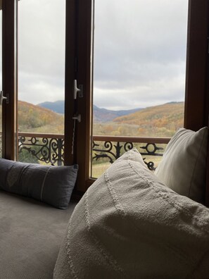 Quarto com vista para colinas outonais através de amplas janelas.