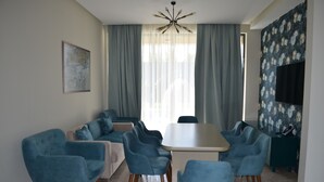 A modern living room with a dining area, featuring a large table and multiple blue armchairs. - Arena Villas Guba (Quba)