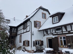 Een traditioneel vakwerkhuis met een met sneeuw bedekte kap en een duidelijke voordeur.