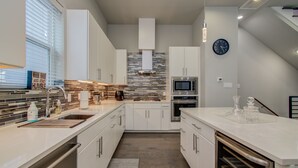 A modern kitchen with white cabinetry, a tiled backsplash, and stainless steel appliances. - Luxurious Houston NRG/Medical Center Townhome (Houston)