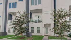 A modern multi-story residential building with balconies, large windows, and a well-maintained lawn. - Luxurious Houston NRG/Medical Center Townhome (Houston)