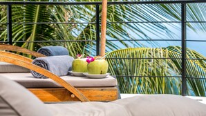 A balcony with a wooden chair, a cushion, and two coconuts with drinks and flowers. - Room B8 - PANORAMIC SEA VIEW (Koh Samui)